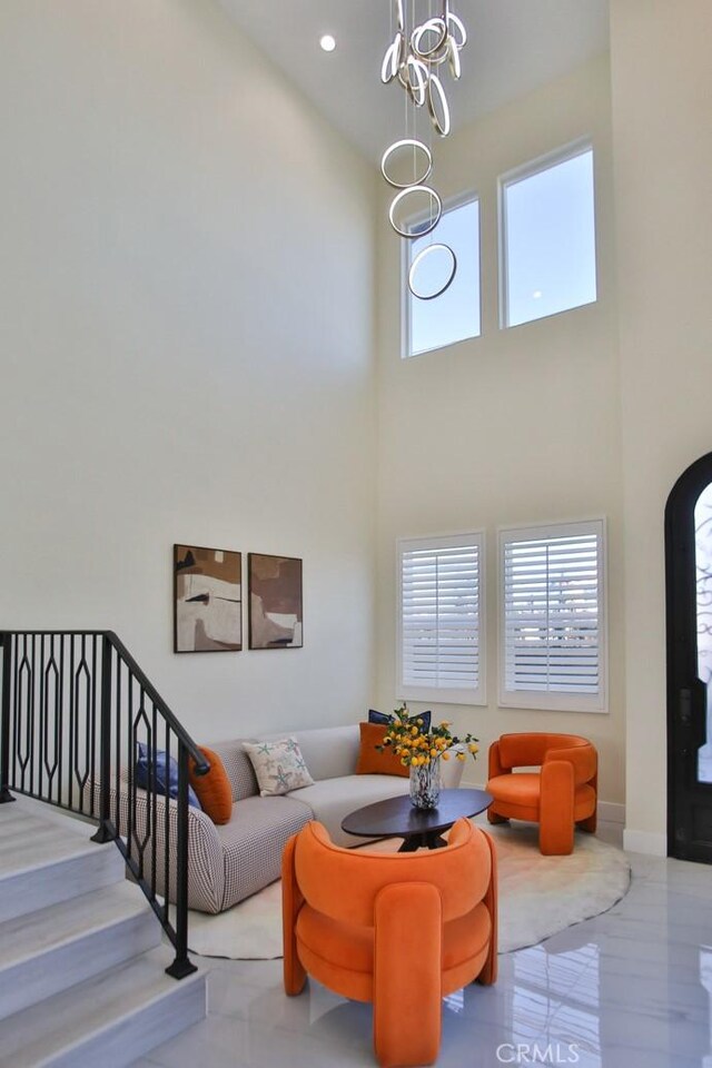 living room with a towering ceiling, plenty of natural light, and a notable chandelier