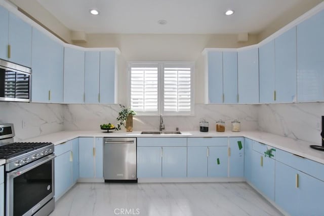 kitchen with stainless steel appliances, sink, blue cabinets, and decorative backsplash