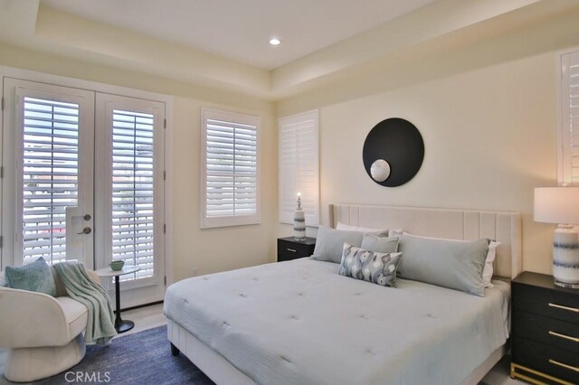 bedroom with a tray ceiling, access to outside, and french doors