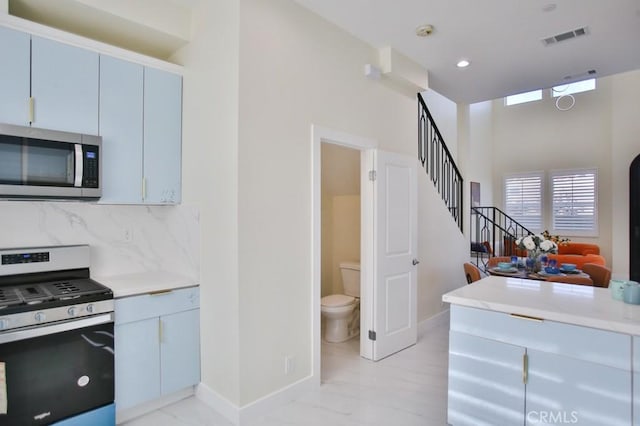 kitchen with tasteful backsplash, baseboards, visible vents, stainless steel appliances, and light countertops