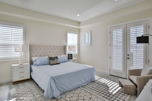 bedroom featuring access to outside, multiple windows, and baseboards