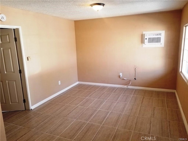 unfurnished room featuring an AC wall unit and a textured ceiling