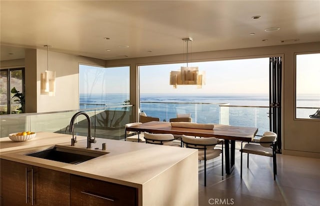 kitchen featuring sink, decorative light fixtures, a healthy amount of sunlight, and a water view