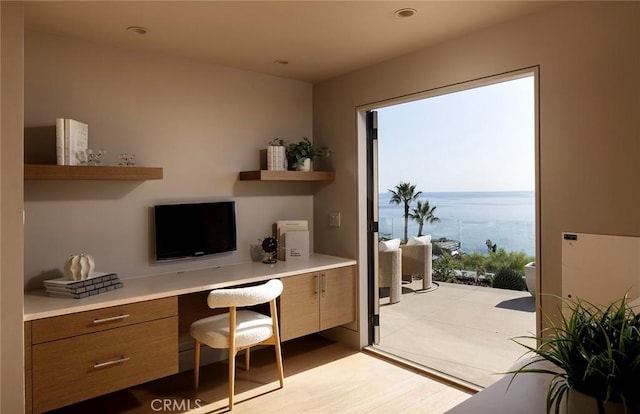 home office with built in desk and light wood-type flooring