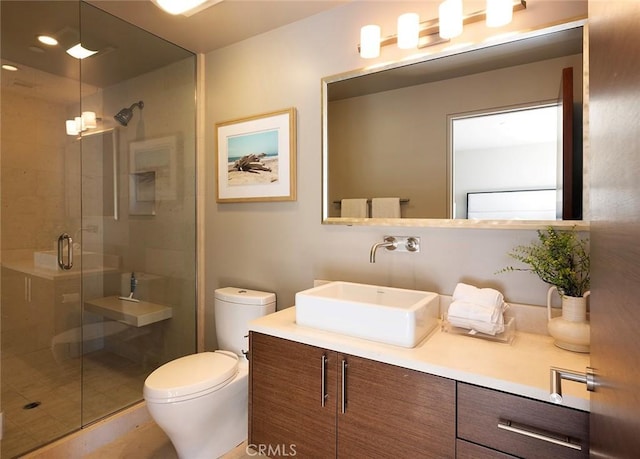 bathroom featuring toilet, vanity, and a shower with shower door