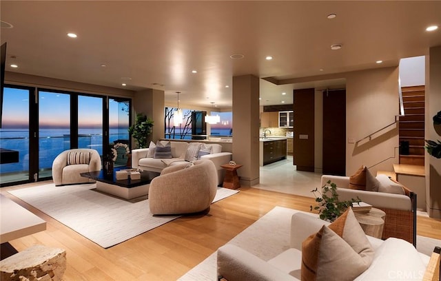 living room with a water view, sink, and light hardwood / wood-style flooring