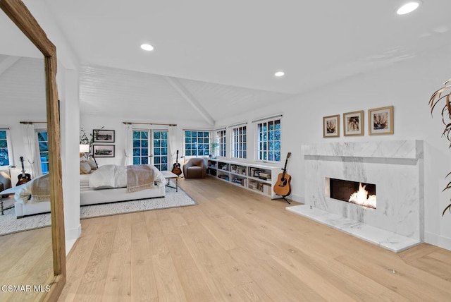 living room featuring vaulted ceiling with beams, a high end fireplace, and light hardwood / wood-style floors