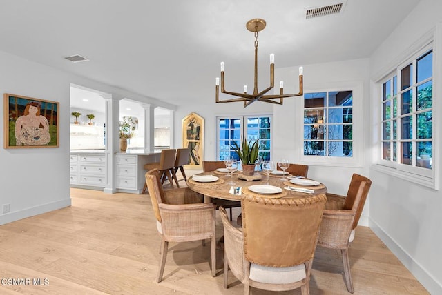 dining area with a notable chandelier, built in desk, and light hardwood / wood-style floors