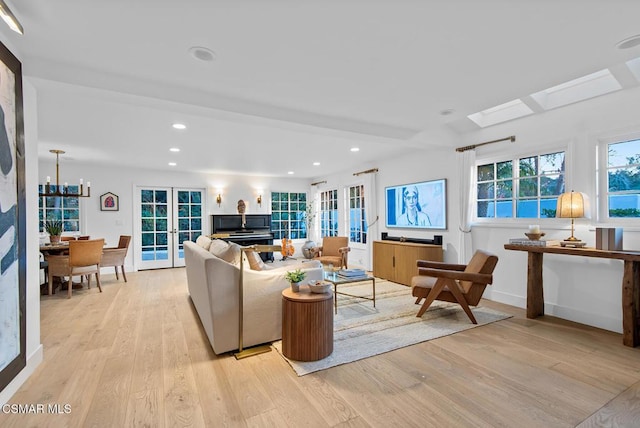 living room featuring a skylight, beam ceiling, light hardwood / wood-style flooring, and french doors