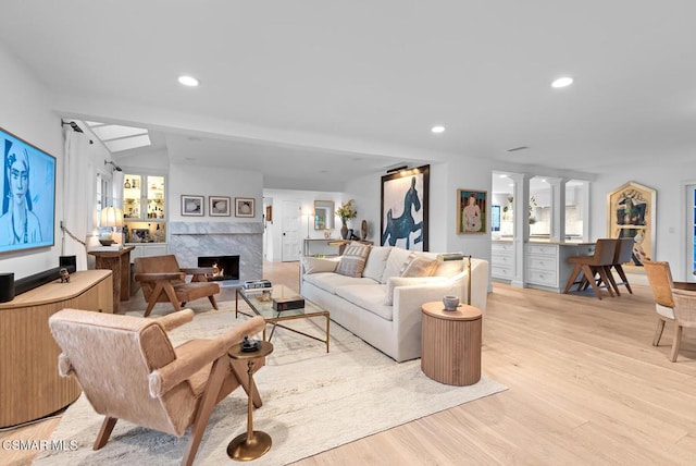 living room featuring lofted ceiling, a high end fireplace, light hardwood / wood-style flooring, and built in desk