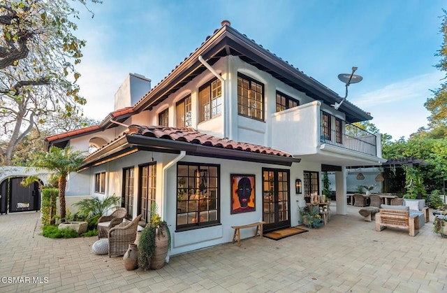 rear view of house featuring french doors, a balcony, and a patio area