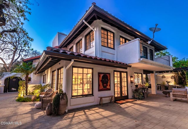 rear view of property with a patio area, french doors, and a balcony