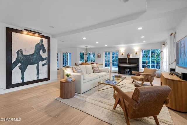 living room featuring french doors, light hardwood / wood-style flooring, and a notable chandelier