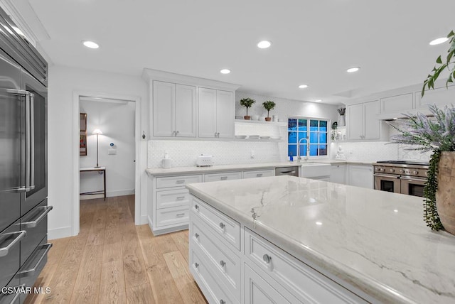 kitchen with white cabinetry, decorative backsplash, light hardwood / wood-style floors, and built in fridge