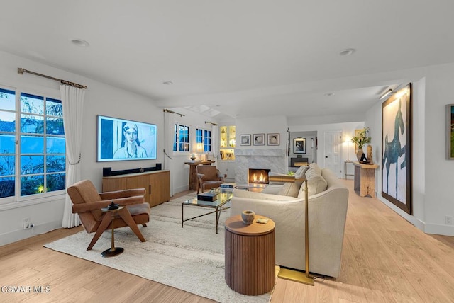 living room with a high end fireplace and light hardwood / wood-style floors