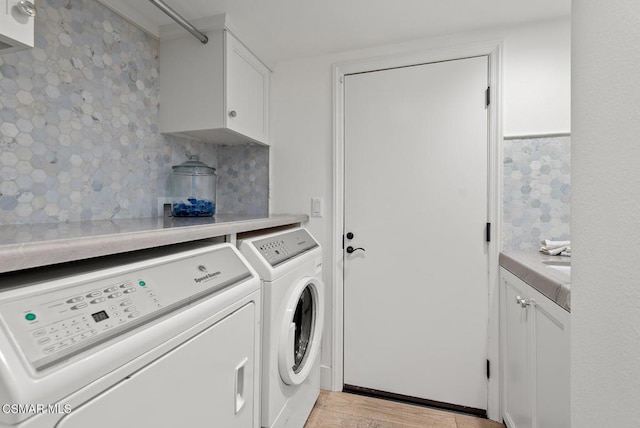 washroom featuring independent washer and dryer, light hardwood / wood-style flooring, and cabinets