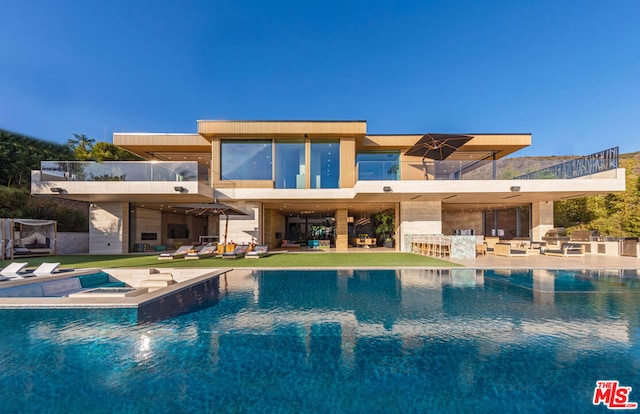 rear view of house with a swimming pool with hot tub, a patio, and exterior bar