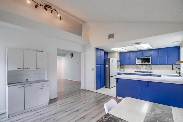 kitchen with blue cabinets, sink, white cabinetry, stainless steel appliances, and decorative backsplash