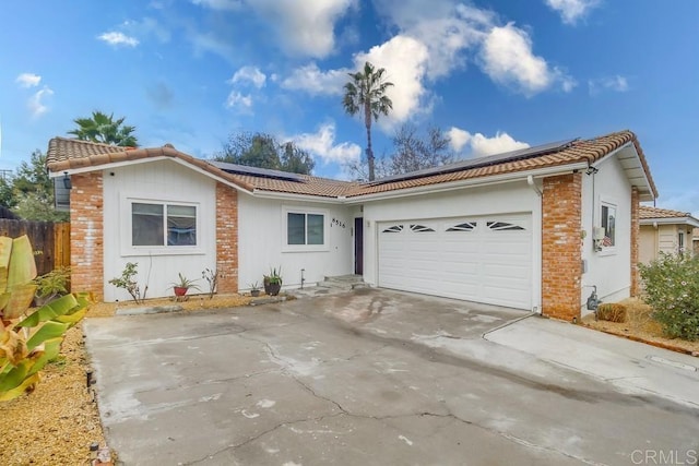 ranch-style home with a garage and solar panels