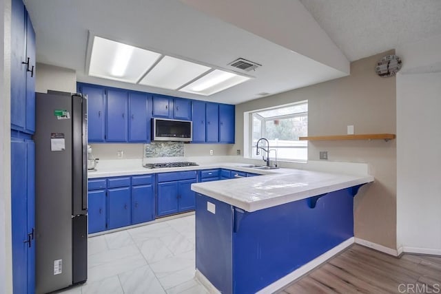 kitchen with blue cabinetry, stainless steel appliances, a kitchen breakfast bar, and kitchen peninsula