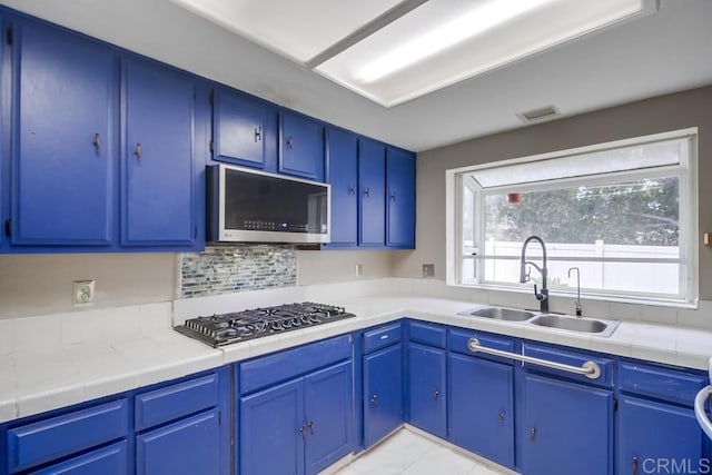 kitchen featuring blue cabinets, sink, decorative backsplash, and appliances with stainless steel finishes