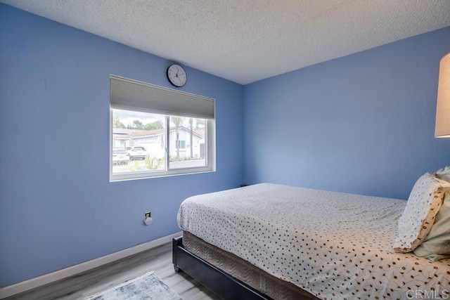 bedroom with light hardwood / wood-style floors and a textured ceiling