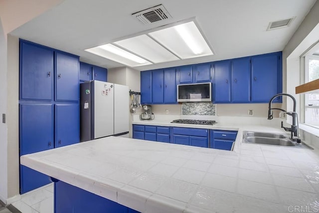 kitchen with appliances with stainless steel finishes, sink, blue cabinetry, and kitchen peninsula