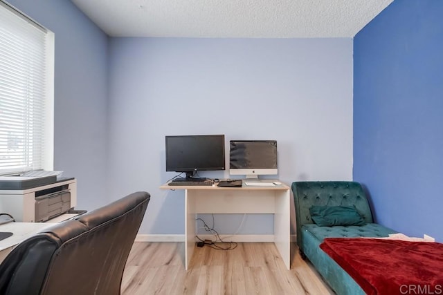 office with light hardwood / wood-style flooring and a textured ceiling