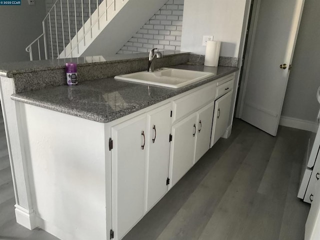 kitchen with sink, white cabinetry, dark hardwood / wood-style flooring, kitchen peninsula, and backsplash