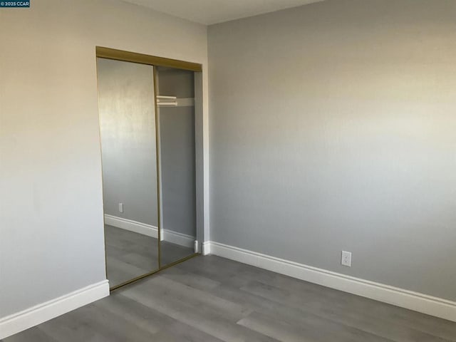 unfurnished bedroom with dark hardwood / wood-style floors and a closet