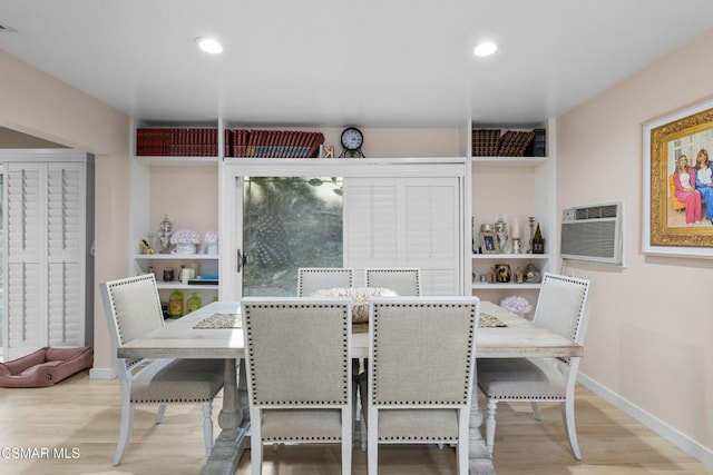 dining room featuring a wall unit AC and light hardwood / wood-style flooring