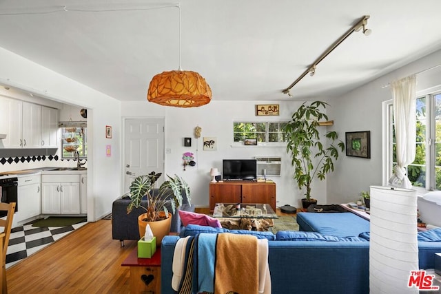 living room with an AC wall unit, rail lighting, sink, and light wood-type flooring