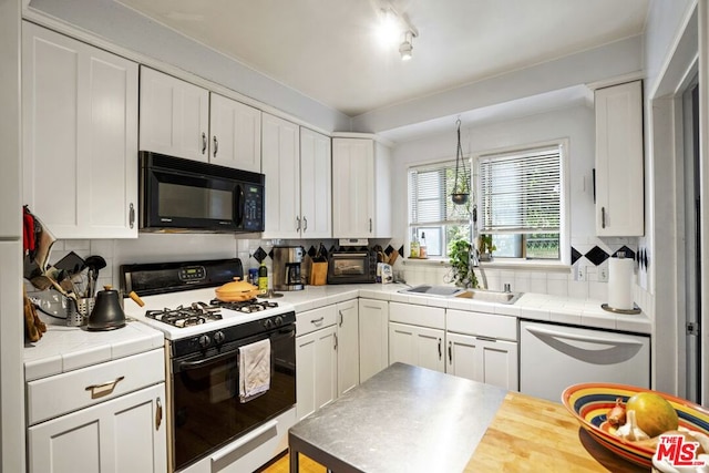 kitchen with tile countertops, range with gas stovetop, dishwasher, sink, and white cabinets