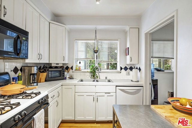 kitchen with dishwashing machine, sink, gas range gas stove, white cabinetry, and decorative light fixtures