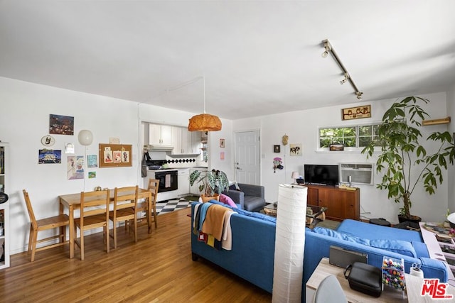 living room with hardwood / wood-style floors, track lighting, and a wall unit AC