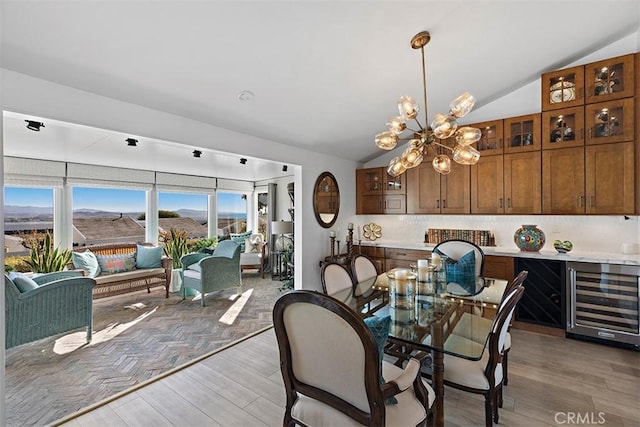 dining space featuring lofted ceiling, hardwood / wood-style flooring, beverage cooler, and a chandelier