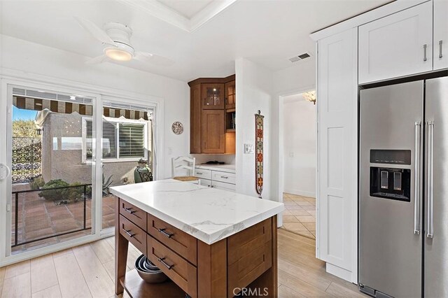 kitchen featuring light stone counters, ceiling fan, high end refrigerator, and light wood-type flooring