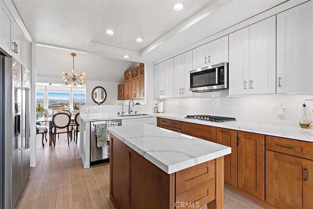 kitchen with pendant lighting, sink, appliances with stainless steel finishes, white cabinets, and a kitchen island