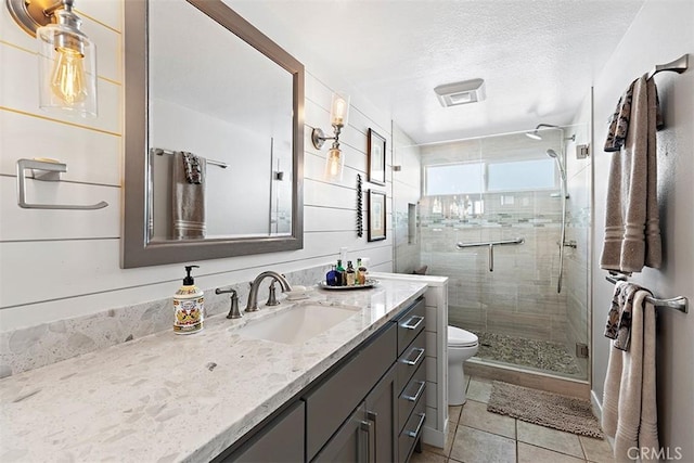 bathroom featuring vanity, toilet, a shower with door, tile patterned floors, and a textured ceiling