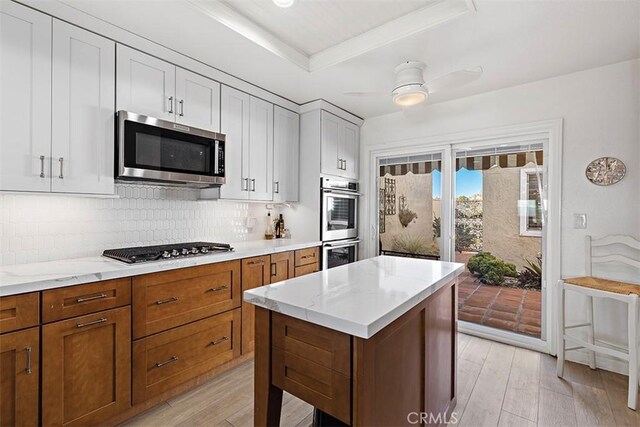 kitchen featuring backsplash, a center island, ceiling fan, light hardwood / wood-style floors, and stainless steel appliances