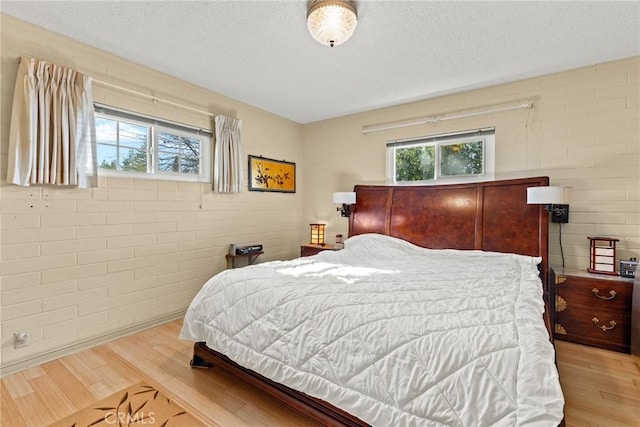 bedroom with a textured ceiling and light wood-type flooring