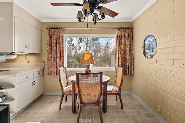 dining room featuring crown molding, ceiling fan, and brick wall