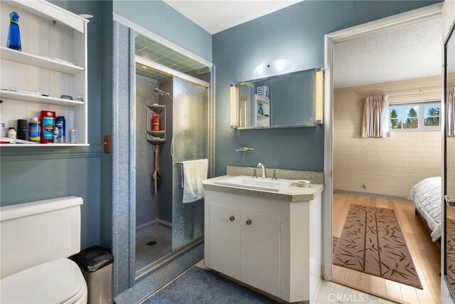 bathroom featuring wood-type flooring, a shower with shower door, vanity, and toilet