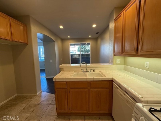 kitchen featuring sink, tile countertops, light tile patterned floors, kitchen peninsula, and dishwasher