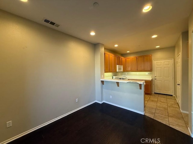 kitchen featuring a kitchen bar, kitchen peninsula, and light tile patterned floors