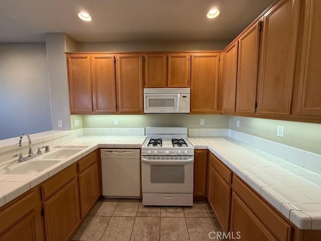 kitchen with white appliances, tile counters, sink, and light tile patterned floors