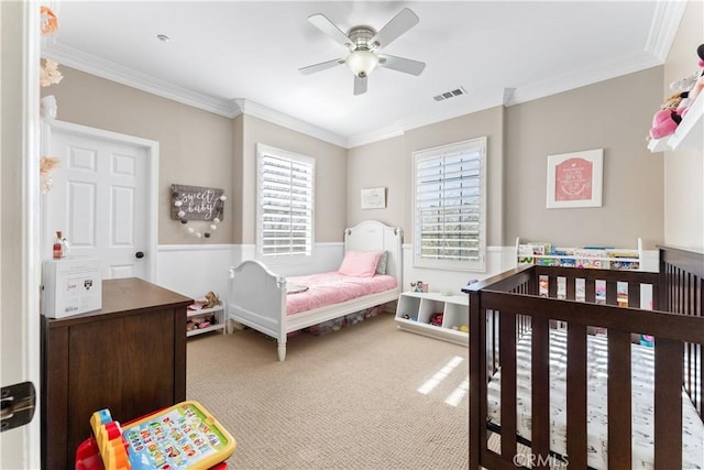 carpeted bedroom featuring a crib, ornamental molding, and ceiling fan