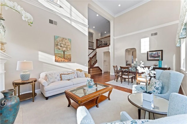 living room featuring crown molding, a healthy amount of sunlight, and a high ceiling