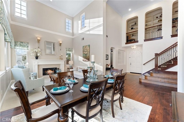 dining space featuring a high ceiling, crown molding, and dark hardwood / wood-style flooring