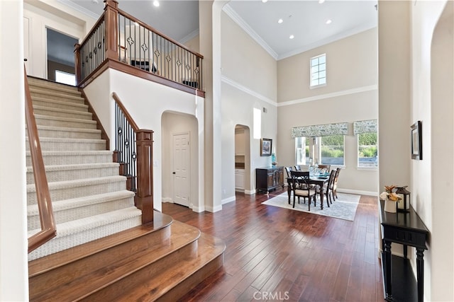 foyer entrance featuring crown molding, a towering ceiling, and dark hardwood / wood-style floors